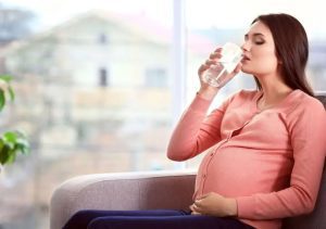 A pregnant lady drinking water to stay hydrated - Managing Pregnancy as a Teacher